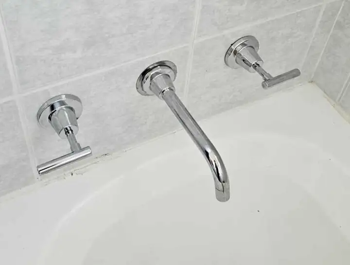 A wall-mounted bath spout and taps