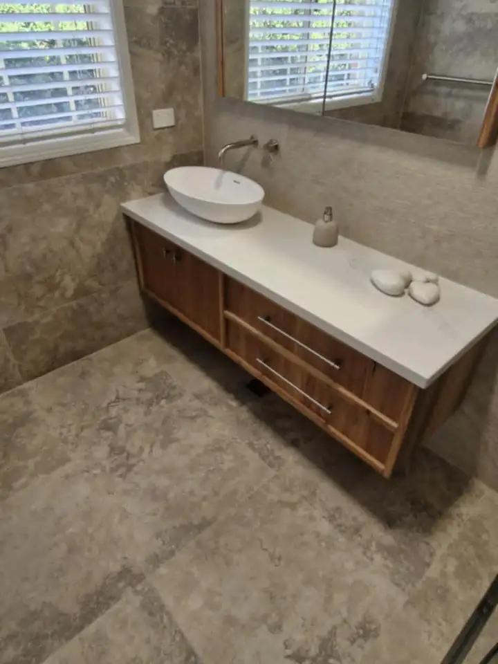 A renovated bathroom with a timber vanity and vessel basin