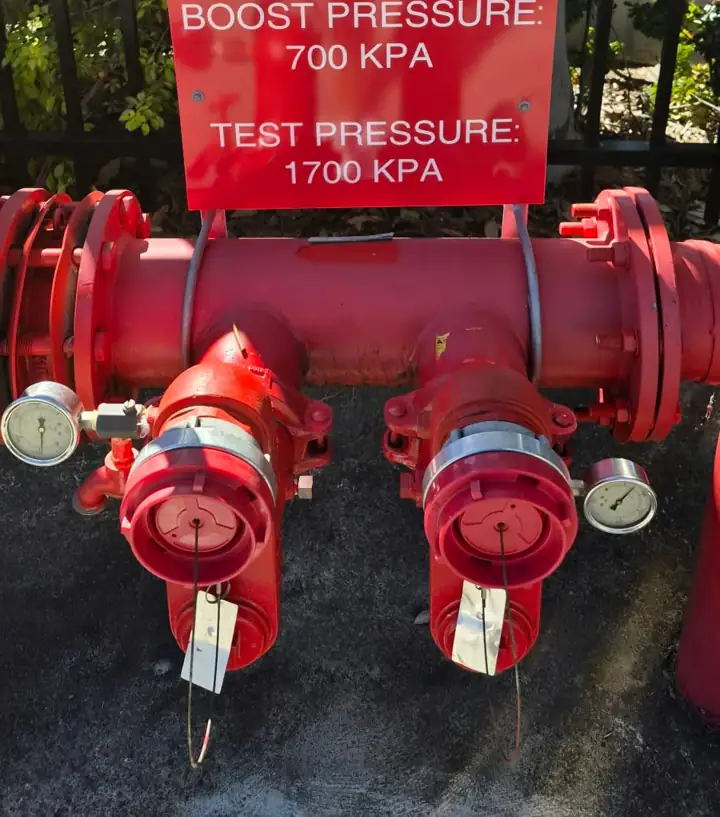 A hydrant booster under its board showing boost and test pressures