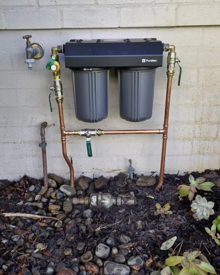 Twin filter housings on an external wall above a garden bed