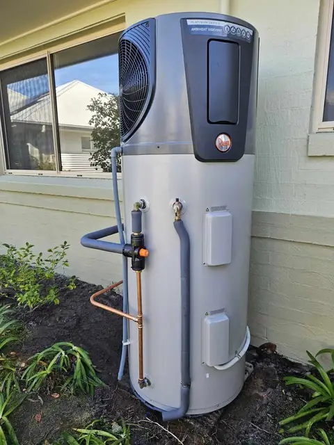 A heat pump hot water unit against a rendered wall