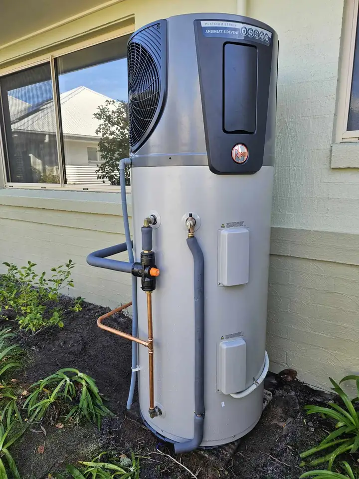 A heat pump hot water unit against a rendered wall
