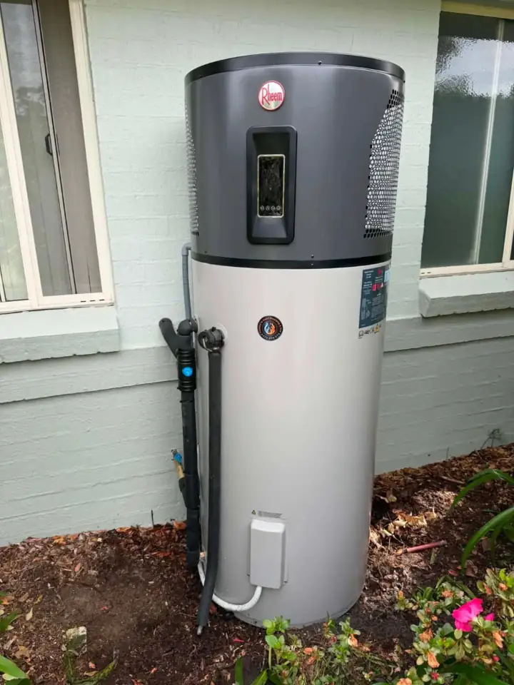 A heat pump hot water unit beside a window