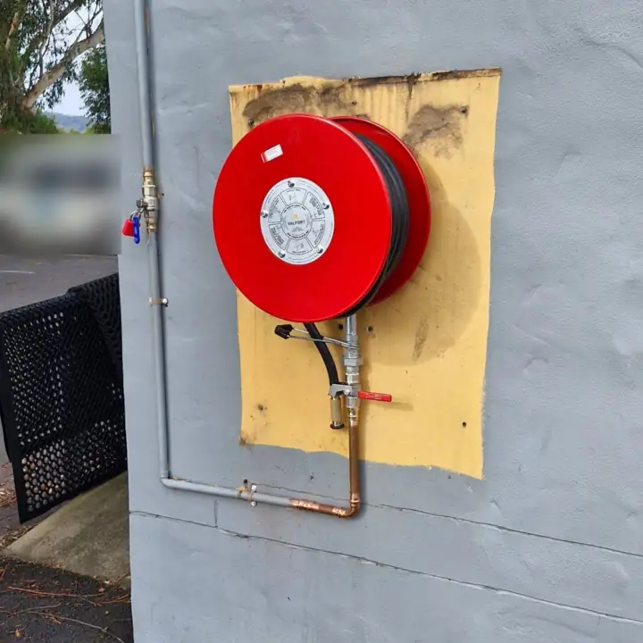 A red fire hose reel on an exterior wall