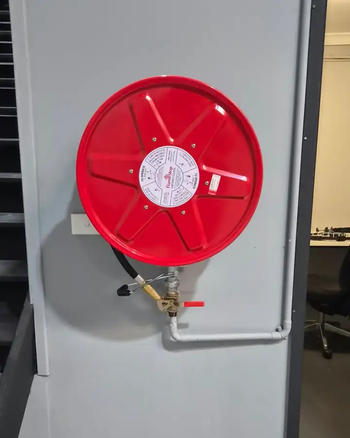 A red fire hose reel on a grey column by an office doorway