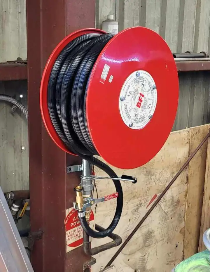 A red fire hose reel on a steel post