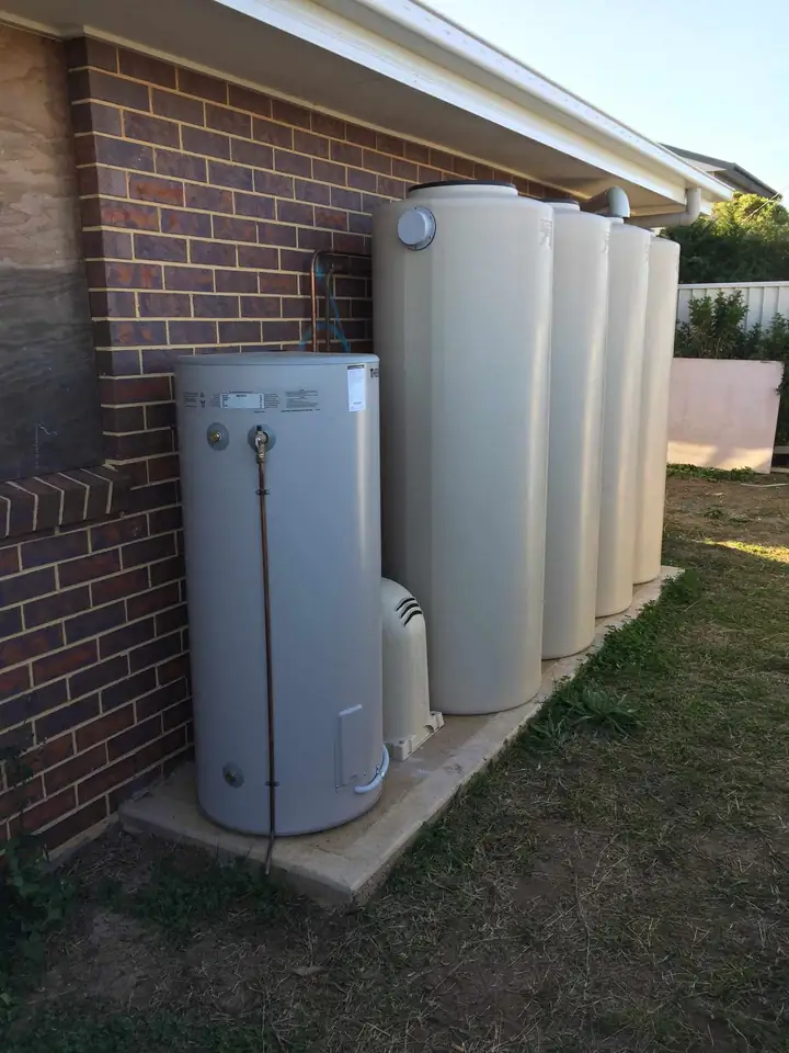 A hot water unit beside a row of rainwater tanks
