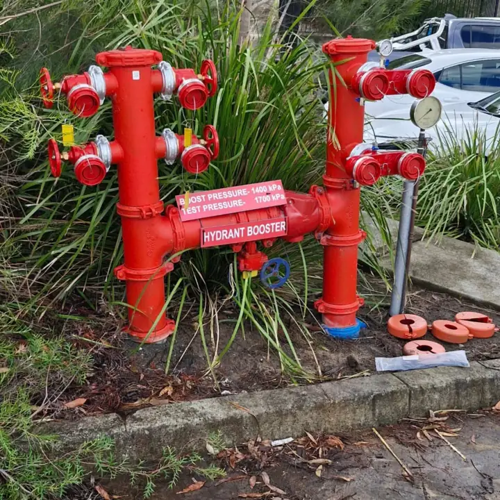 A red hydrant booster assembly with its pressure signage