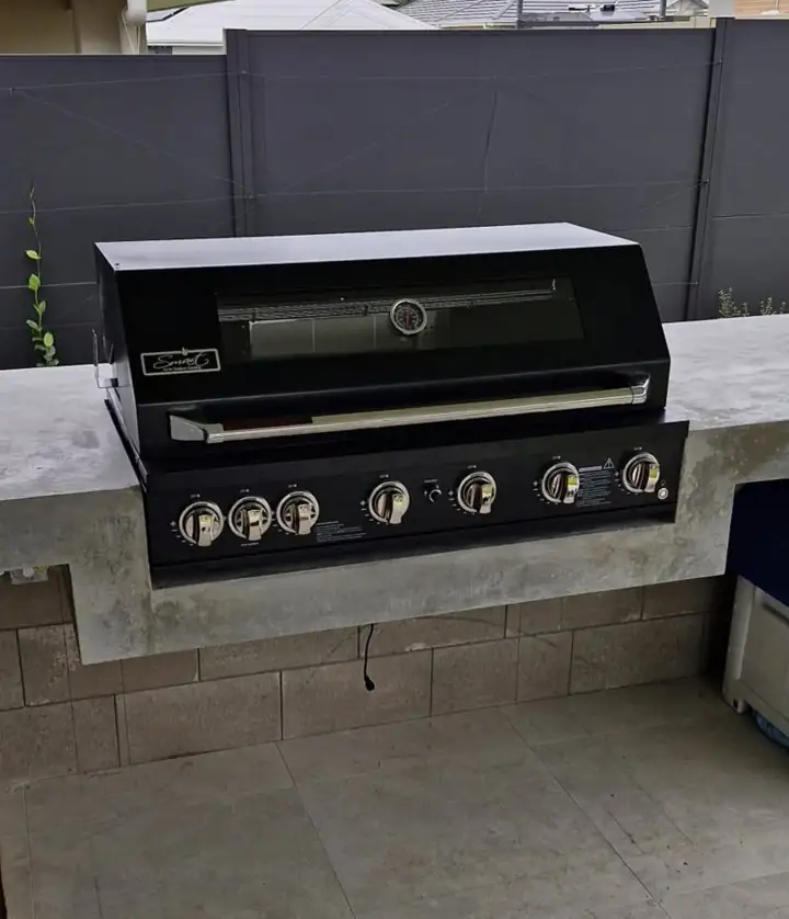 A built-in outdoor barbecue in a concrete bench