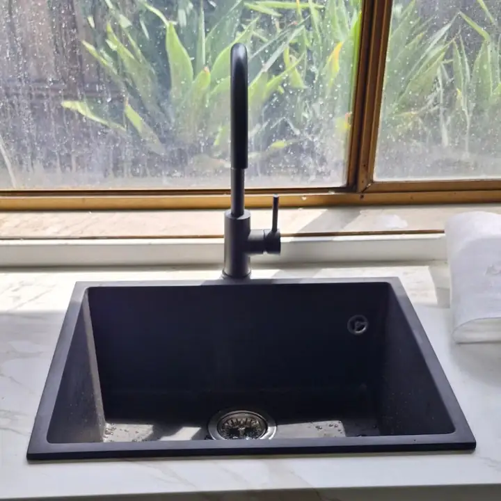 A black mixer over a black undermount sink