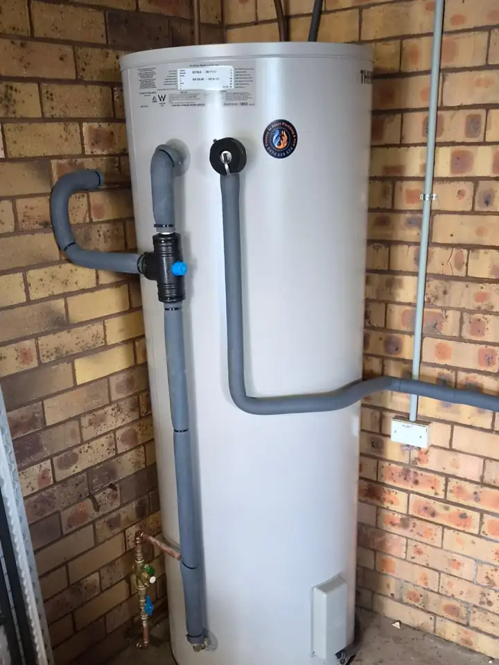 An electric storage hot water unit on a brick wall with new pipework