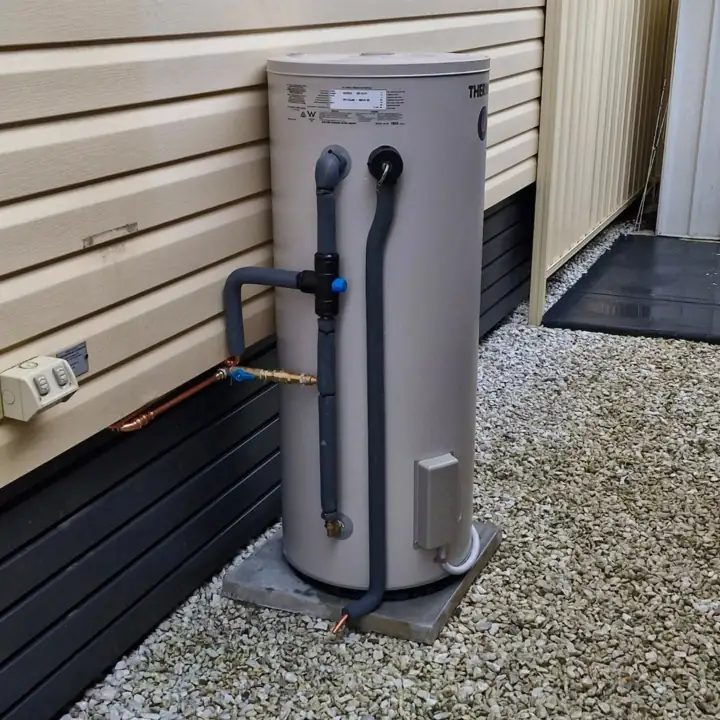 A compact storage hot water unit on a gravel pad