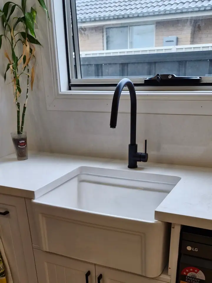 A black gooseneck mixer over a farmhouse sink