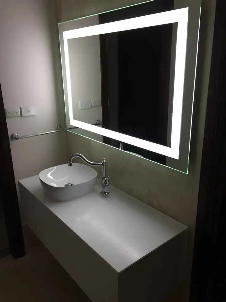 A vanity with a vessel basin under a backlit mirror